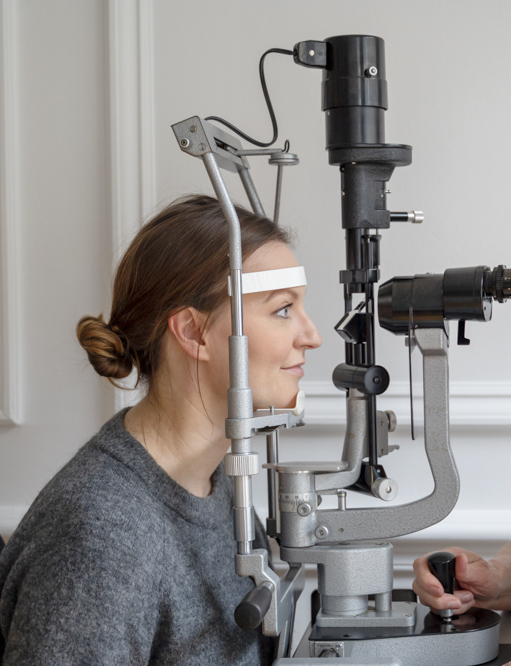 Woman eye doctor examines woman patient's eyes
